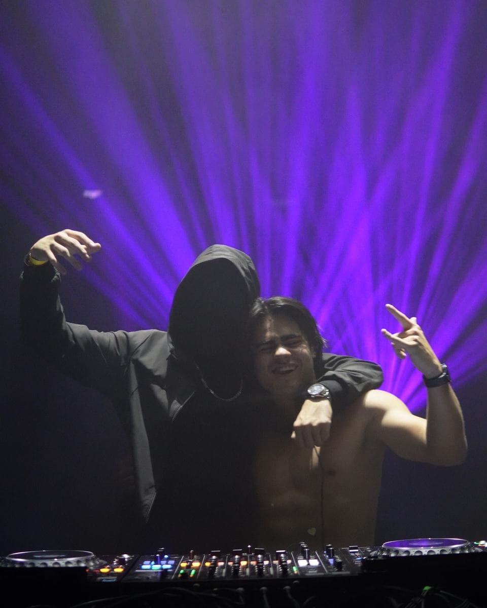 Ryan behind the decks in purple light, with a friend beside him
